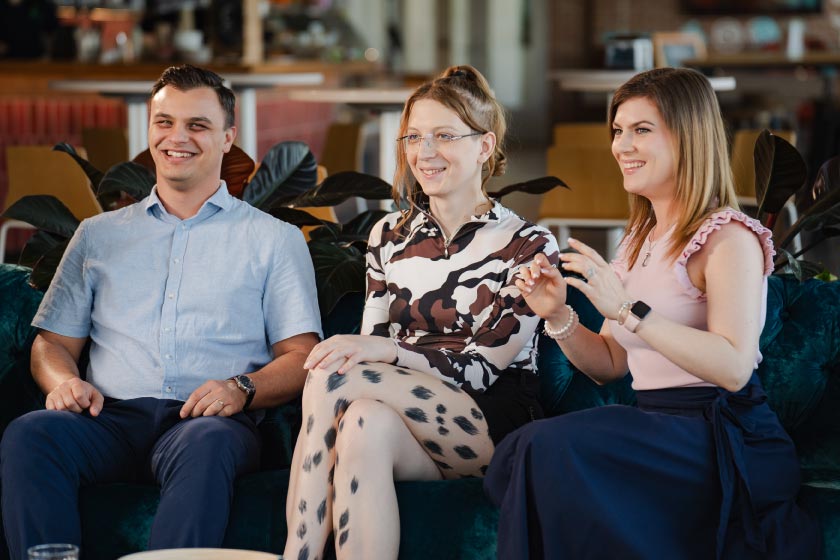 three people sitting indoors smiling.
