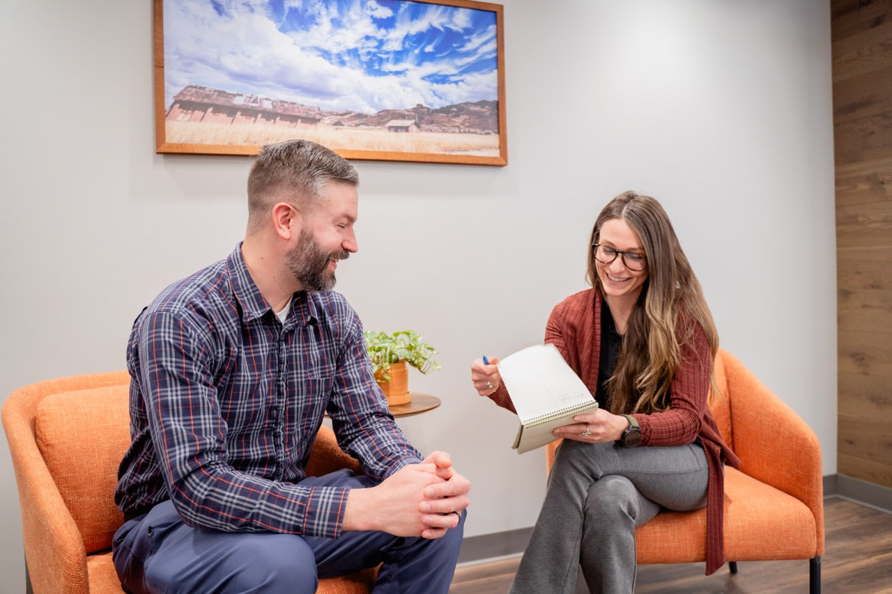 woman talking to man and taking notes